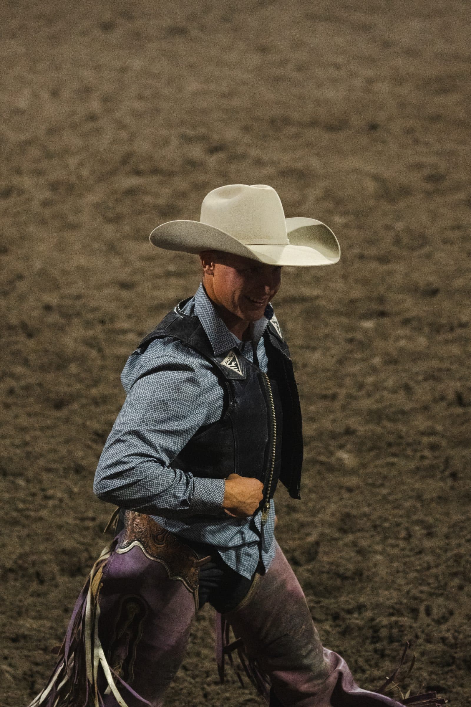 A cowboy in chaps crosses the arena